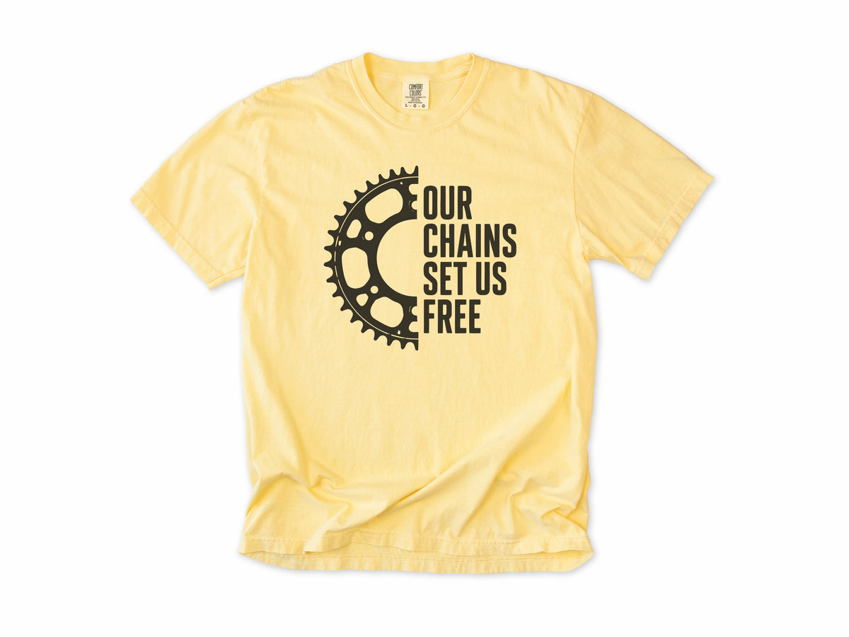 Funny cycling T-shirt in Butter, 'Our Chains Set Us Free' beside a chainring, for cyclists