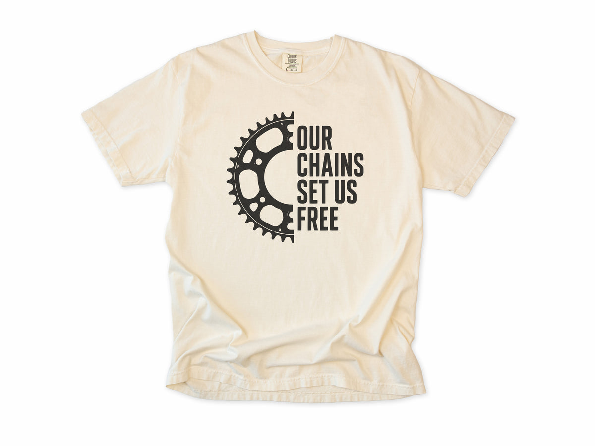 Funny cycling T-shirt in Ivory, 'Our Chains Set Us Free' beside a chainring, for cyclists