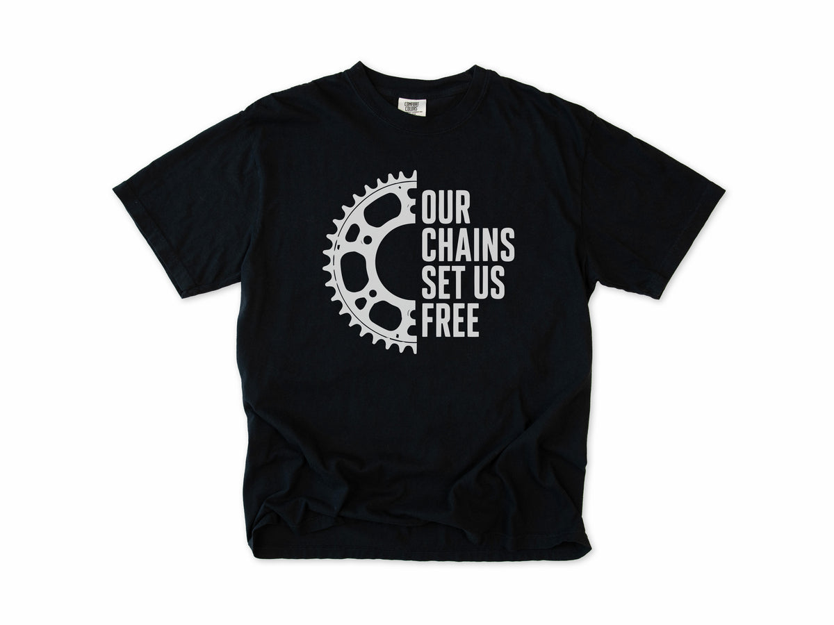 Funny cycling T-shirt in Black, 'Our Chains Set Us Free' beside a chainring, for cyclists