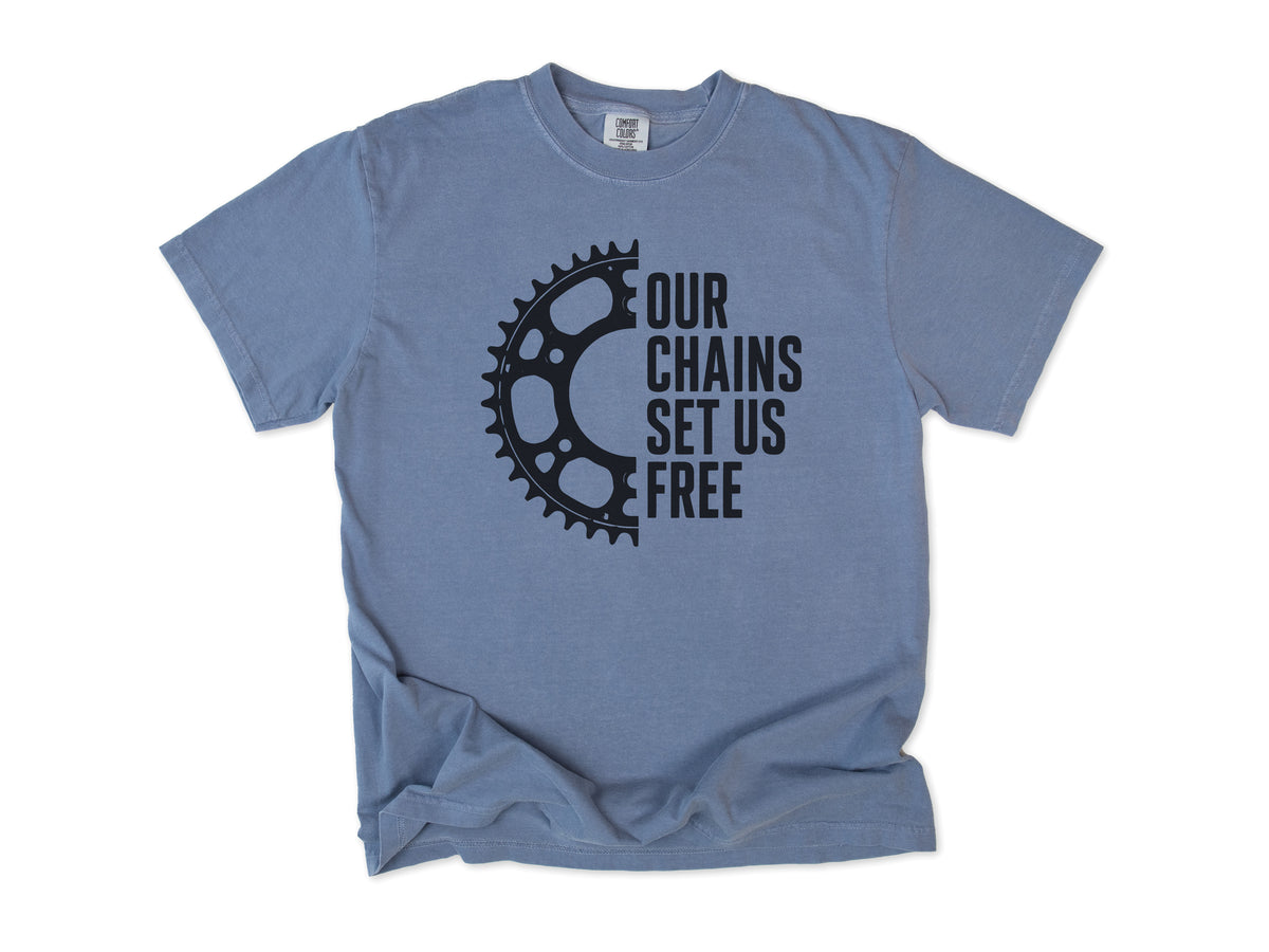 Funny cycling T-shirt in Blue Jean, 'Our Chains Set Us Free' beside a chainring, for cyclists