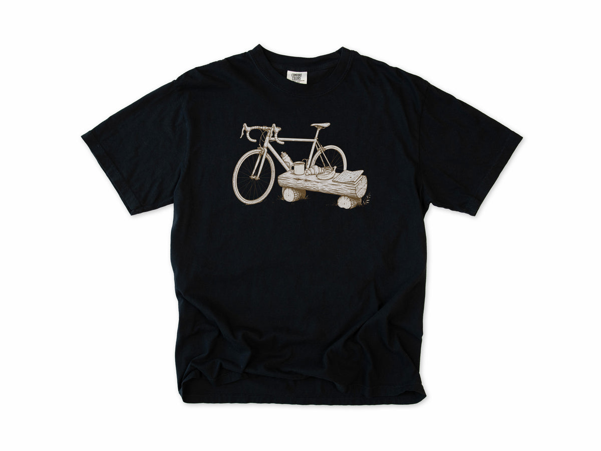 Funny cycling T-shirt in Black, a bike propped on a log with a drink, for gravel and trail riders