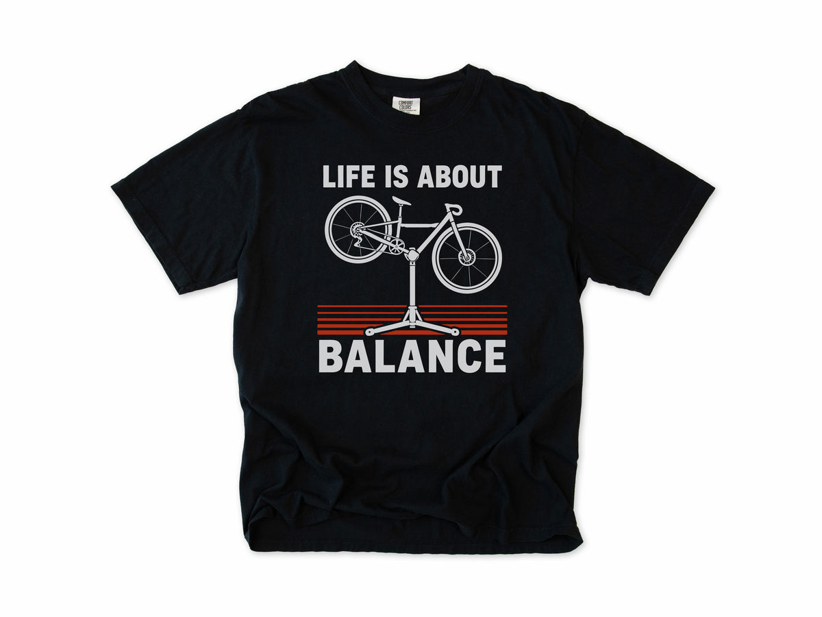 Funny cycling T-shirt in Black, 'Life Is About Balance' with a bike on a repair stand, for cyclists and bike mechanics