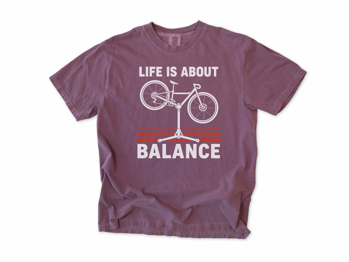 Funny cycling T-shirt in Berry, 'Life Is About Balance' with a bike on a repair stand, for cyclists and bike mechanics