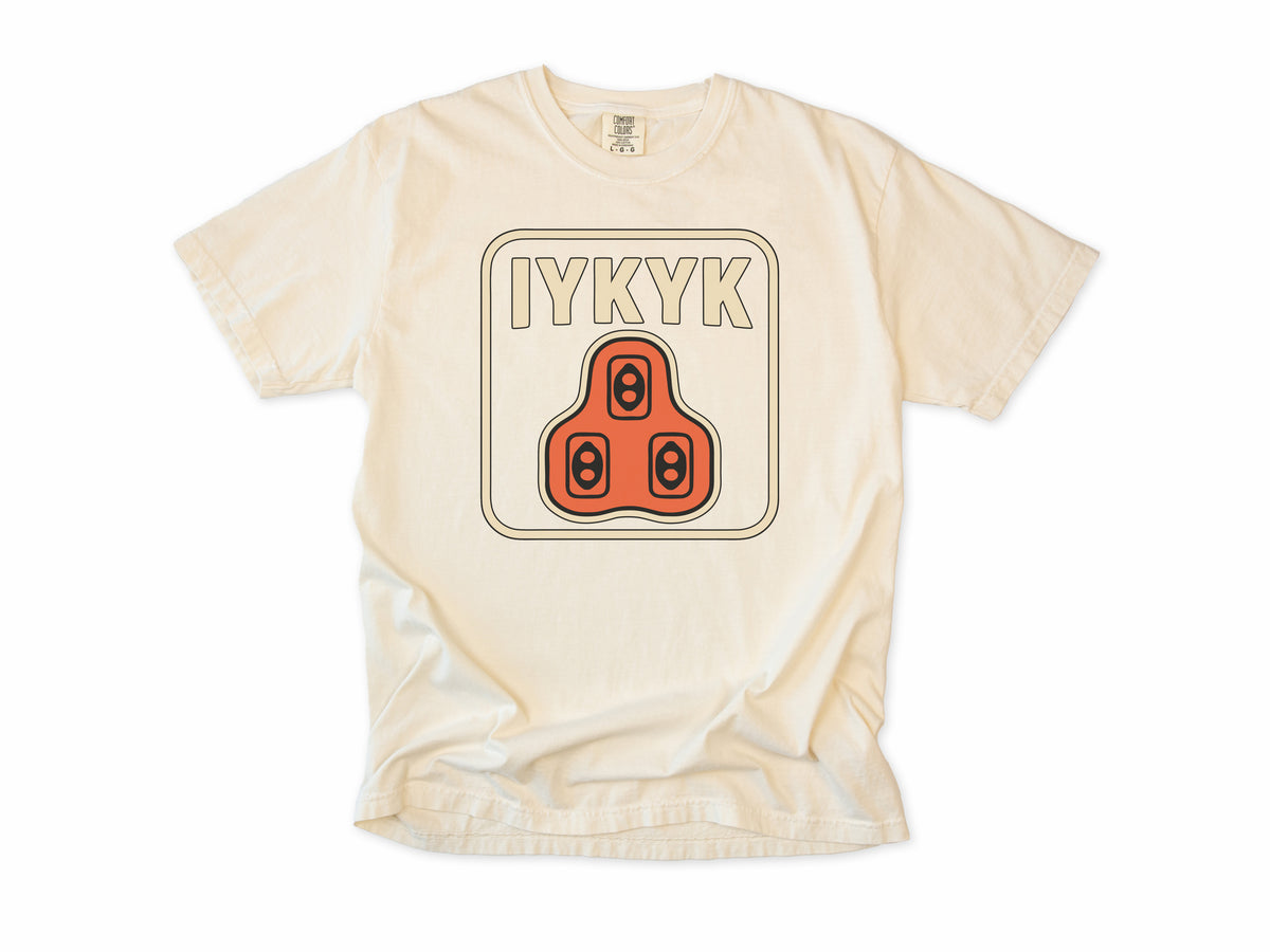 Funny cycling T-shirt in Ivory, 'IYKYK' with an orange road bike cleat, for riders who use clipless pedals
