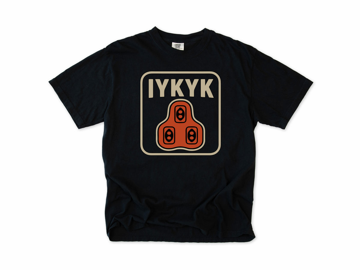 Funny cycling T-shirt in Black, 'IYKYK' with an orange road bike cleat, for riders who use clipless pedals