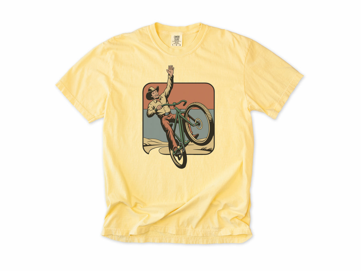 Cycling T-shirt in Butter, Cycling Cowboy: a cowboy doing a wheelie on a bike, in a desert square, for mountain bikers