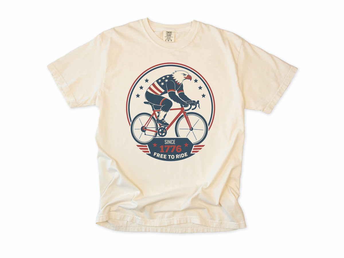 Cycling T-shirt in Ivory, a bald eagle in stars and stripes riding a bike, America 250 and 4th of July gift for cyclists