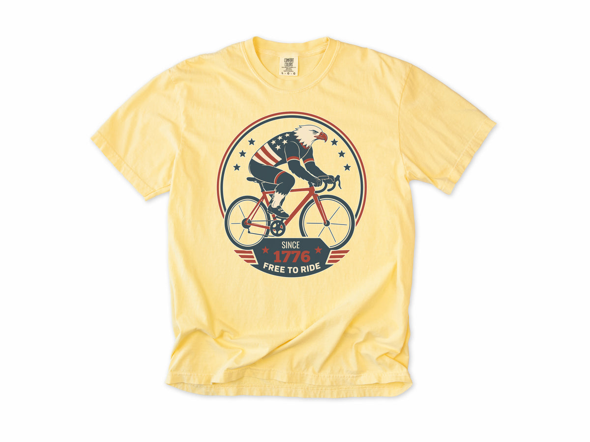 Cycling T-shirt in Butter, a bald eagle in stars and stripes riding a bike, America 250 and 4th of July gift for cyclists