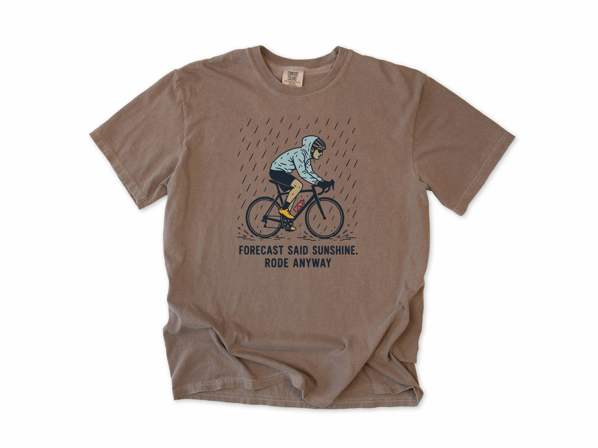 Funny cycling T-shirt in Espresso, a cyclist in the rain, 'Forecast said sunshine. Rode anyway', for all-weather riders
