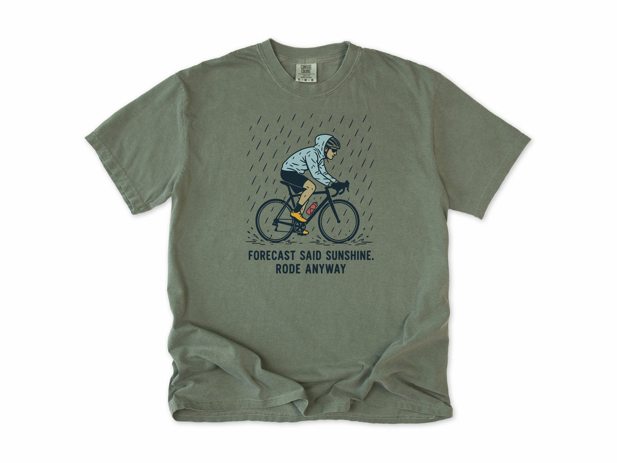 Funny cycling T-shirt in Moss, a cyclist in the rain, 'Forecast said sunshine. Rode anyway', for all-weather riders