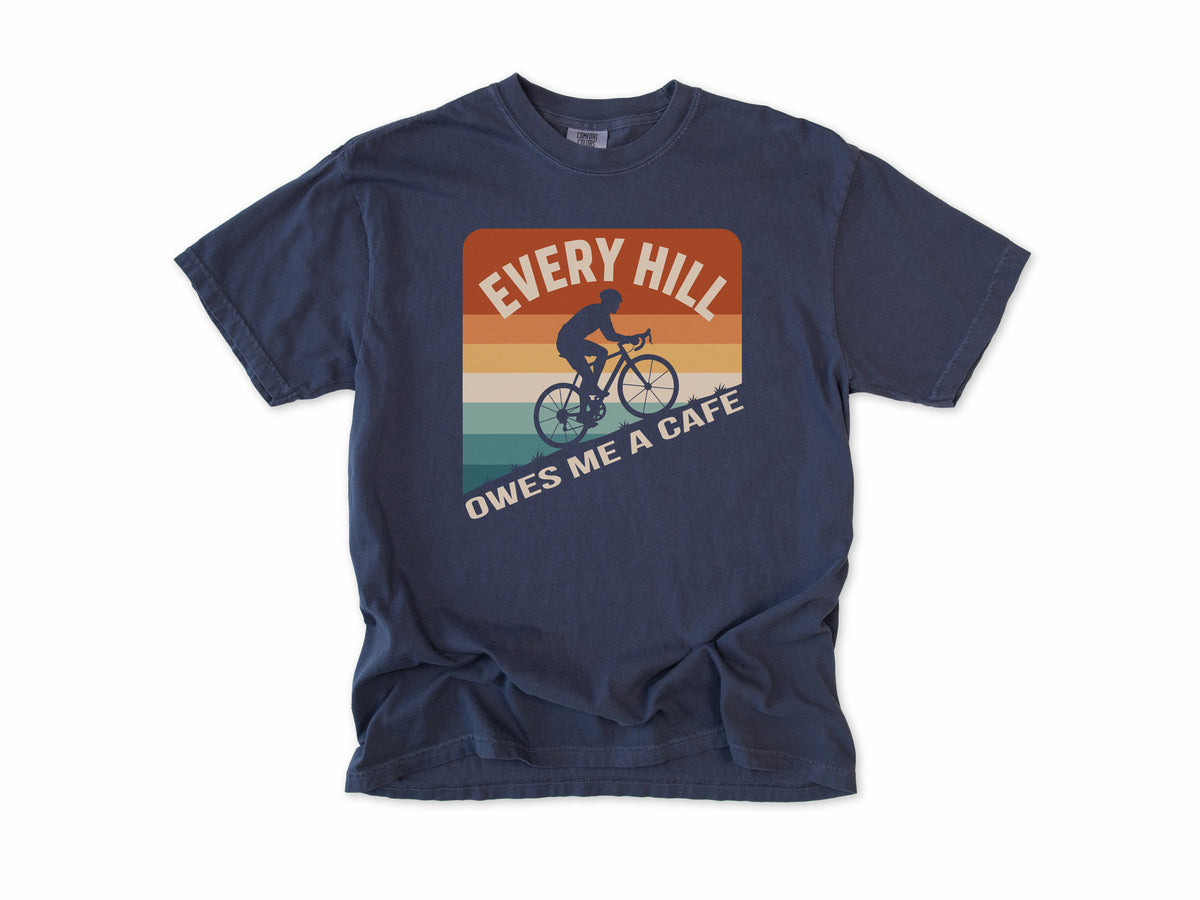 Funny cycling T-shirt in Navy, 'Every Hill Owes Me a Cafe', a cyclist on retro stripes, for riders who ride for coffee