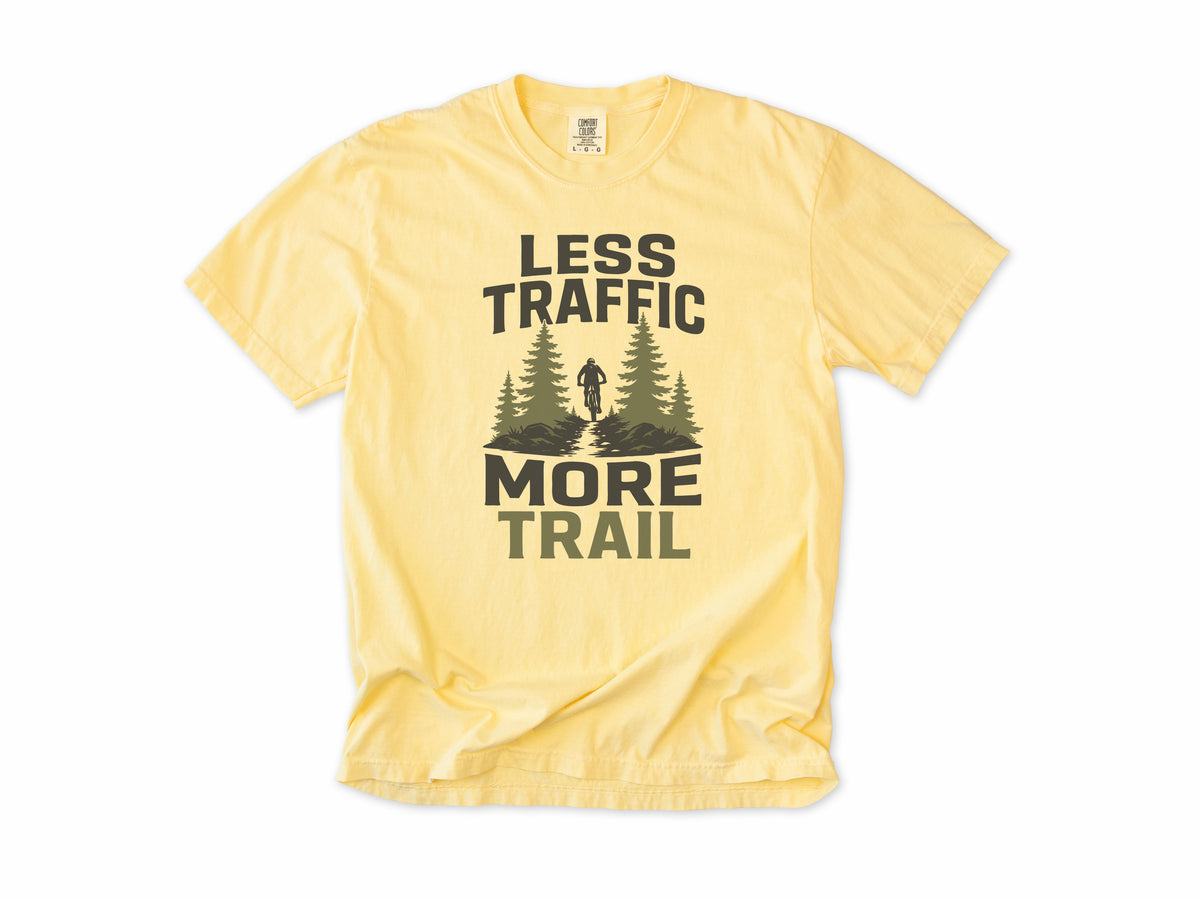 Cycling T-shirt in Butter, 'Less Traffic More Trail' with a rider between pine trees, for mountain bikers