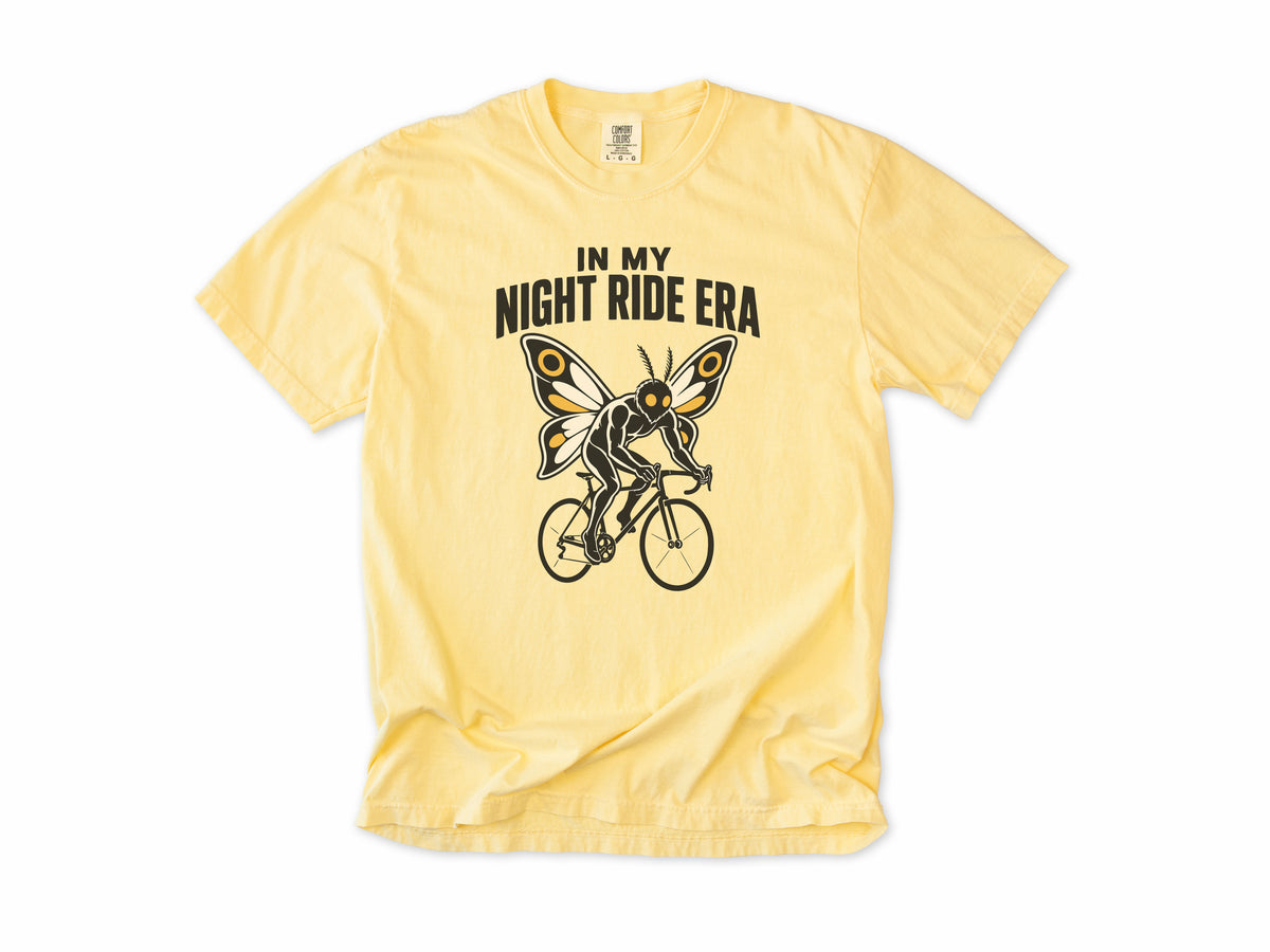 Funny cycling T-shirt in Butter, Mothman Single: 'In my night ride era', a moth-winged figure riding a bike, for night riders