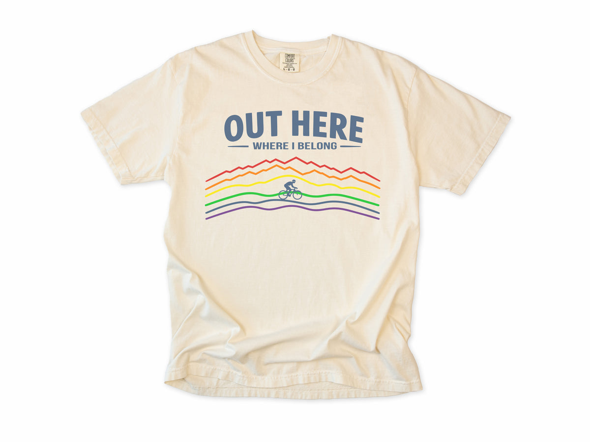 Cycling T-shirt in Ivory, 'Out Here Where I Belong' with rainbow mountain lines and a cyclist, for outdoor cyclists