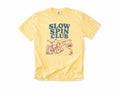 Cycling T-shirt in Butter, 'Slow Spin Club' with a bike on a winding country lane, for relaxed riders