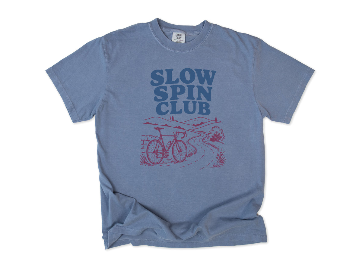 Cycling T-shirt in Blue Jean, 'Slow Spin Club' with a bike on a winding country lane, for relaxed riders
