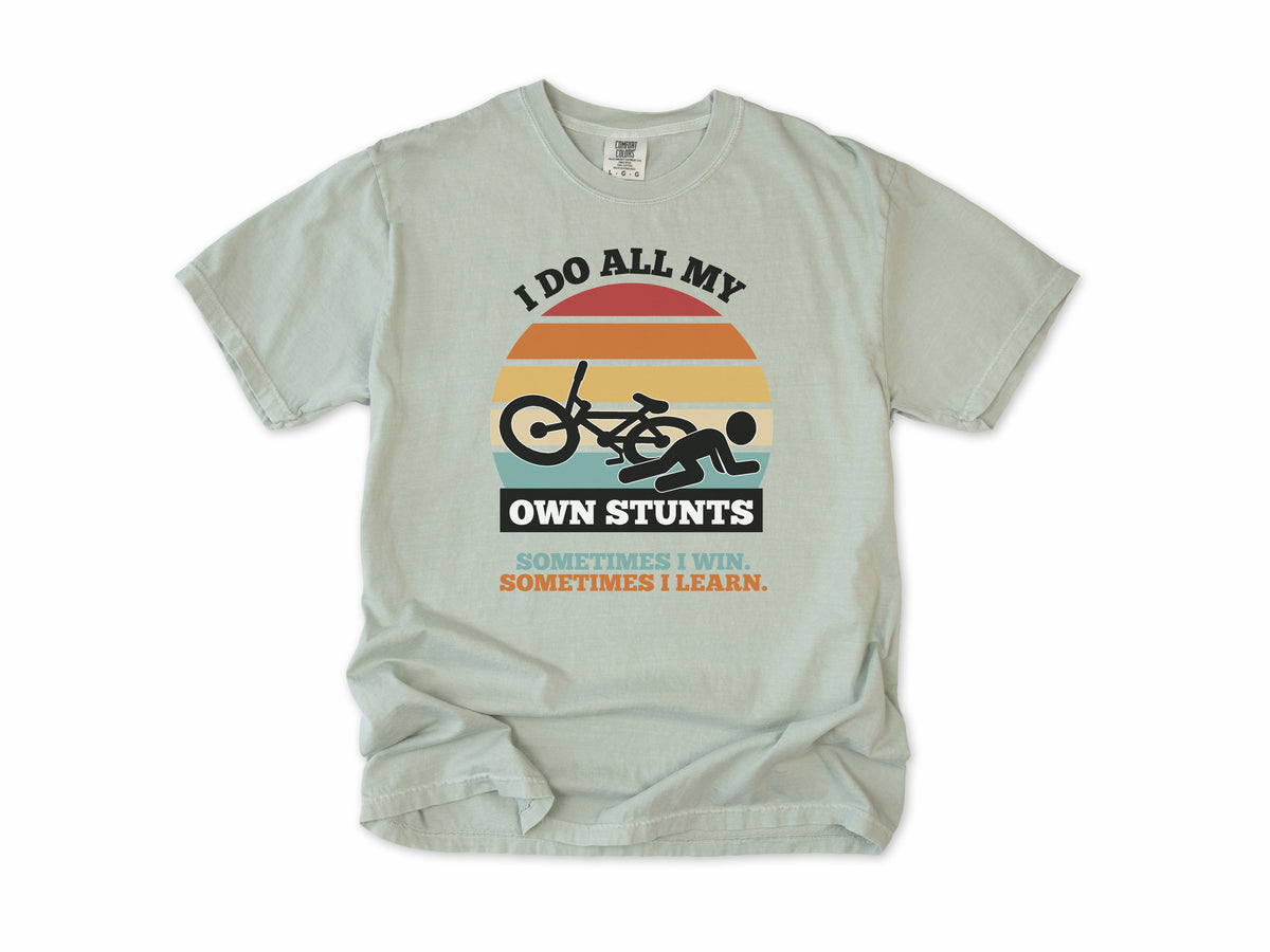 Funny cycling T-shirt in Bay, 'I Do All My Own Stunts', a crashed rider on retro sunset stripes, for mountain bikers