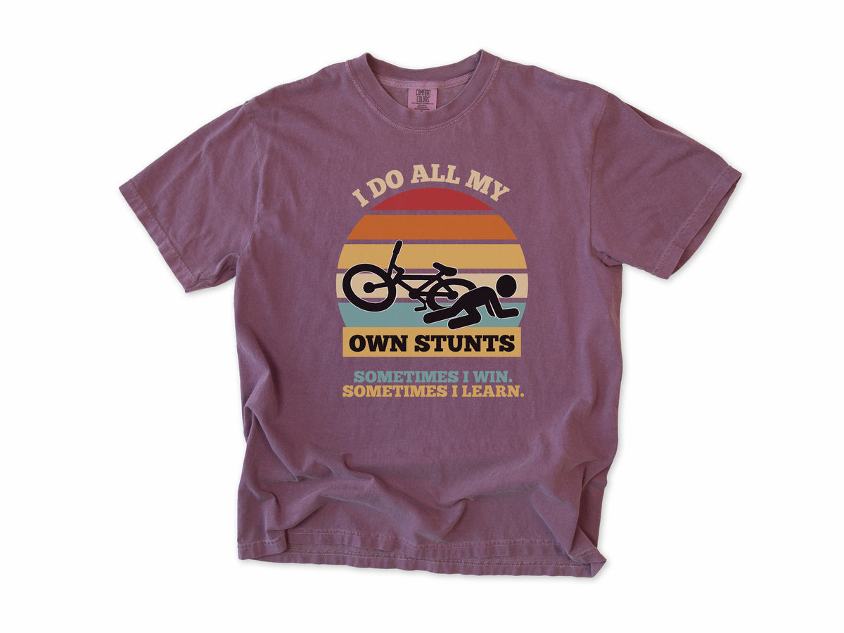 Funny cycling T-shirt in Berry, 'I Do All My Own Stunts', a crashed rider on retro sunset stripes, for mountain bikers