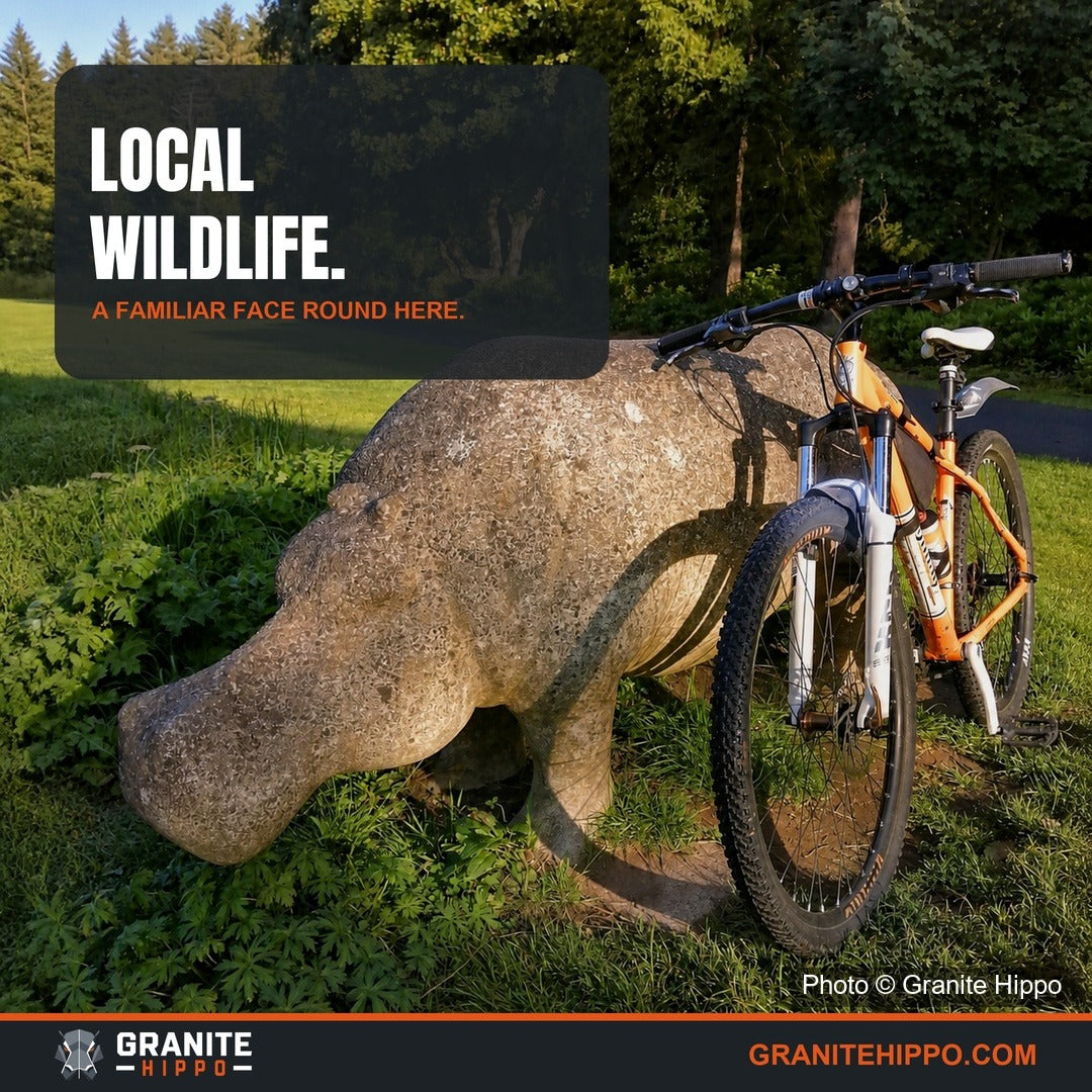 A bicycle beside a local stone hippo in a park